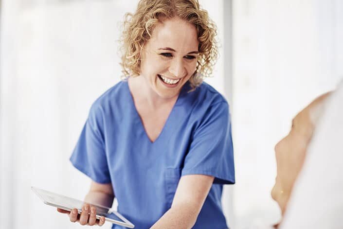 smiling nurse looking after patient in bed